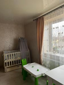Zimmer mit Kinderbett, Tisch und Fenster in der Unterkunft DALIM in Duliby