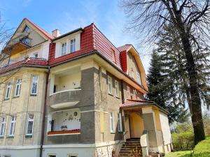 une grande maison avec un toit rouge dans l'établissement Apartament Daisy, à Szczawno-Zdrój