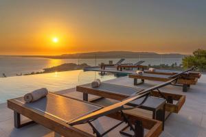 een zwembad met tafels en de zonsondergang op de achtergrond bij Echos Villa in Argostoli