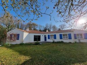 uma casa branca com persianas azuis num quintal em MAISON OROUET PISCINE 4 CHAMBRES em Saint-Jean-de-Monts