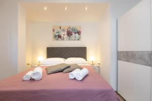 sypialnia z różowym łóżkiem i ręcznikami w obiekcie Apartman Ruza w Krku
