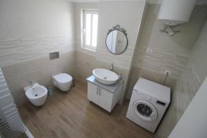 a bathroom with a toilet sink and a washing machine at Nefeli Apartments in Sarandë