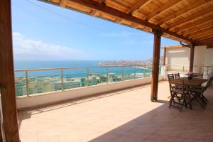 a balcony with a table and chairs and the ocean at Nefeli Apartments in Sarandë