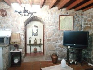 a living room with a tv and a stone wall at CASIÑA OS LUEIRO in Portas