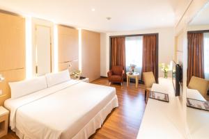 um quarto de hotel com uma cama grande e uma televisão em Zenith Sukhumvit Hotel - SHA Extra Plus em Bangkok