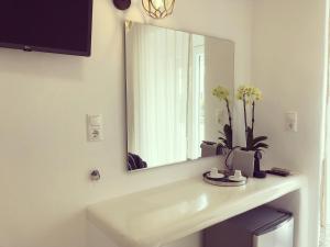 La salle de bains est pourvue d'un lavabo, d'un miroir et de fleurs. dans l'établissement Taki's Guests, à Naxos Chora