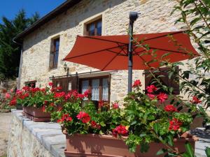 an umbrella in front of a building with flowers at Les dessous de la grange in Larroque-Toirac
