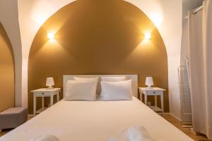 een slaapkamer met een groot wit bed met 2 lampen bij LES VOÛTES DE SATURNIN in Saint-Saturnin