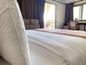 a bedroom with a large white bed with a window at Veronica Guest House in Lomé