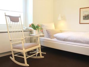 1 dormitorio con mecedora junto a la cama en Eremitage Sylt, en Wenningstedt