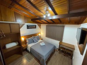 een slaapkamer met een bed en een flatscreen-tv bij Residencia Hencke Haus in Canela