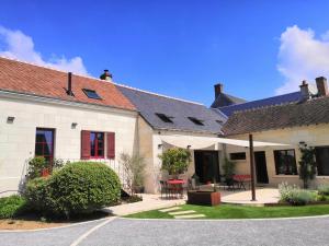 a white building with a courtyard with tables and chairs at Cottage l'Orée du Cher in Chissay-en-Touraine