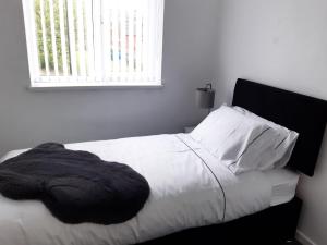 a bedroom with a bed with white sheets and a window at Cheerful home close to the city and Peak District in Neepsend
