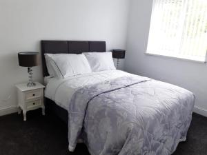 a bedroom with a bed and a night stand with a lamp at Cheerful home close to the city and Peak District in Neepsend