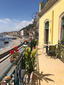 Un balcón con mesas y sillas y vistas al océano. en Hostel Beach House en Giardini Naxos