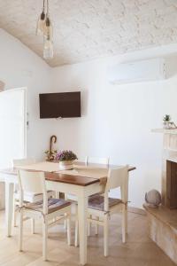 une salle à manger blanche avec une table et des chaises en bois dans l'établissement Trullo La Dama Forestiera, à Alberobello