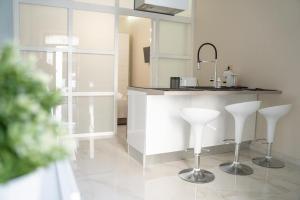 een keuken met twee witte krukken en een aanrecht bij THE HOUSE OF EVELYN in Catania