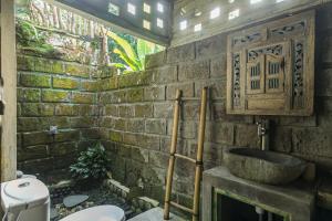 a stone bathroom with a sink and a toilet at Tepi Sawah Lodge & Retreat in Jatiluwih