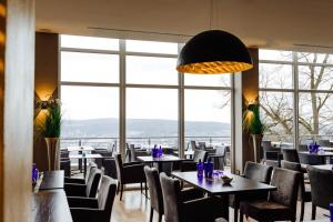 ein Restaurant mit Tischen und Stühlen und großen Fenstern in der Unterkunft Klüt Hotel in Hameln