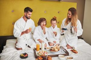 eine Familie, die im Bett sitzt und Essen isst in der Unterkunft Radisson Blu Sobieski in Warschau