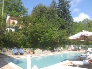 a swimming pool with chairs and an umbrella at Vacanze Toscane In The Country in Sassetta