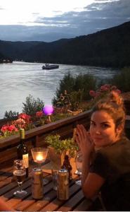 a woman sitting at a table with a view of a river at Villa Christina in Kamp-Bornhofen