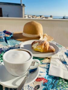 a hat and a cup of coffee and a pastry on a table at B&B La Rosa dei Venti in Vieste