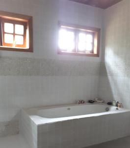 une baignoire blanche dans une salle de bain avec deux fenêtres dans l'établissement CASA EM MONTE VERDE CHARME E CONFORTO, à Monte Verde 68 autres photos