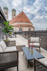 un patio all'ultimo piano con sedie e tavoli e un edificio di DO & CO Hotel München a Monaco
