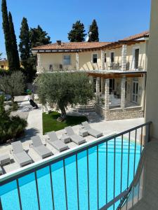 a swimming pool with lounge chairs next to a house at Hotel Baia dei Pini in Torri del Benaco