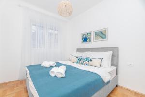 a white bedroom with a large bed with towels on it at Central One-Bedroom Apartment in Budva