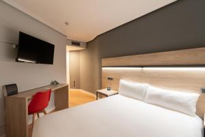 a bedroom with a white bed and a red chair at Alda Centro Zaragoza in Zaragoza