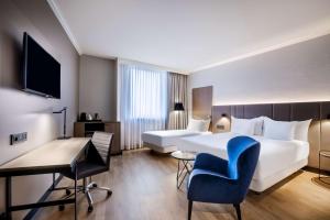 ルクセンブルクにあるNH ルクセンブルクのベッドとデスクが備わるホテルルームです。