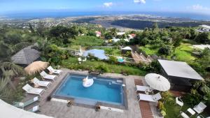 an overhead view of a swimming pool with lounge chairs and an ocean at VILLA GARRIGA in Le Bois de Nèfles