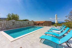 een zwembad met blauwe stoelen naast een stenen muur bij Villa Green Point in Grižane