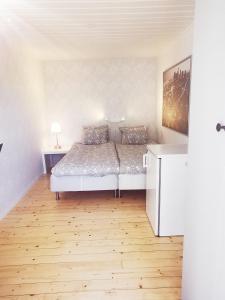 - une chambre blanche avec un lit et du parquet dans l'établissement Villa Neptuni lägenhet och rumsuthyrning, à Byxelkrok