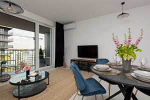 salon ze stołem i niebieskimi krzesłami w obiekcie SOHO 18 Apartment by Renters Prestige w Warszawie