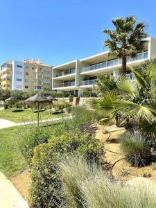 a building with palm trees and plants in front of it at NEW STUNNING OCEAN APRT IN "OASIS MAR" Wi-Fi in Portimão