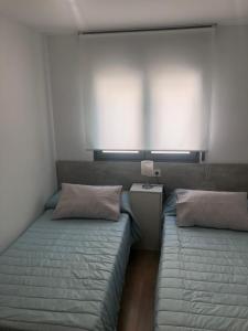 sypialnia z 2 łóżkami i stolikiem nocnym z lampką w obiekcie Apartamento Maracena C/ Ramón y Cajal w mieście Maracena