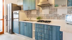 a kitchen with blue cabinets and a stove at Welcomely - Coral Coast Alghero in Alghero