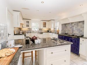 een grote keuken met witte kasten en blauwe apparatuur bij Rose Cottage in Abergavenny