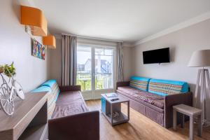 a living room with a couch and a tv at Le Bécasseau Sanderling in Courseulles-sur-Mer