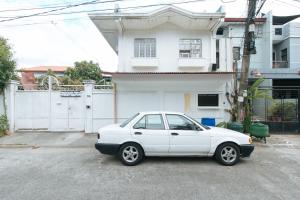 een witte auto geparkeerd voor een huis bij RedDoorz @ Malibu Room BF International Las Pinas in Manilla