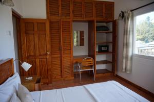 a bedroom with a bed and a chair and a window at La Villa Therese in Anse Royale