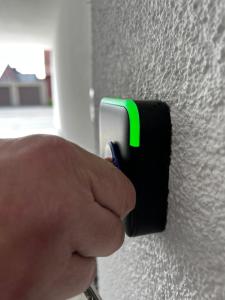 a person pressing a green light on a wall at kleines boardinghouse in Nordwalde