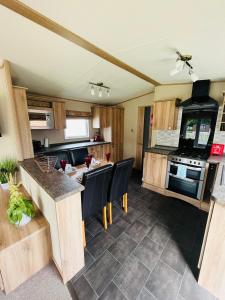 an open kitchen with wooden cabinets and black appliances at Brooksbank Lodge with Hot Tub in Barmby on the Moor