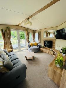 a living room with a couch and a tv at Brooksbank Lodge with Hot Tub in Barmby on the Moor