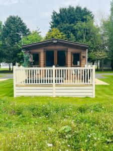 a small cabin in a park with a white fence at Brooksbank Lodge with Hot Tub in Barmby on the Moor