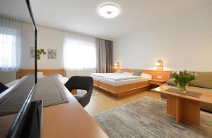 Habitación de hotel con 2 camas y sofá en NATIONALPARKHOF GARTNER Weingut-Gästehaus, en Illmitz