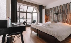 a bedroom with a large bed with a desk and a window at Hotel Cavalli by WP Hotels in Blankenberge
